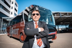 Busfahrer steht mit cooler Pose und Sonnenbrille vor einem rotem BÜSSING DER SCHMIDT Bus am SchmidtTerminal 2025