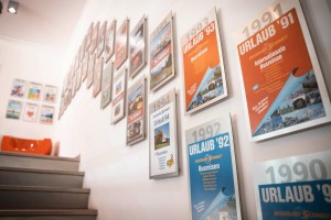 Eingangsbereich DER SCHMIDT mit historischer Katalogwand aus den unterschiedlichen Katalogjahren 1990 bis 2025