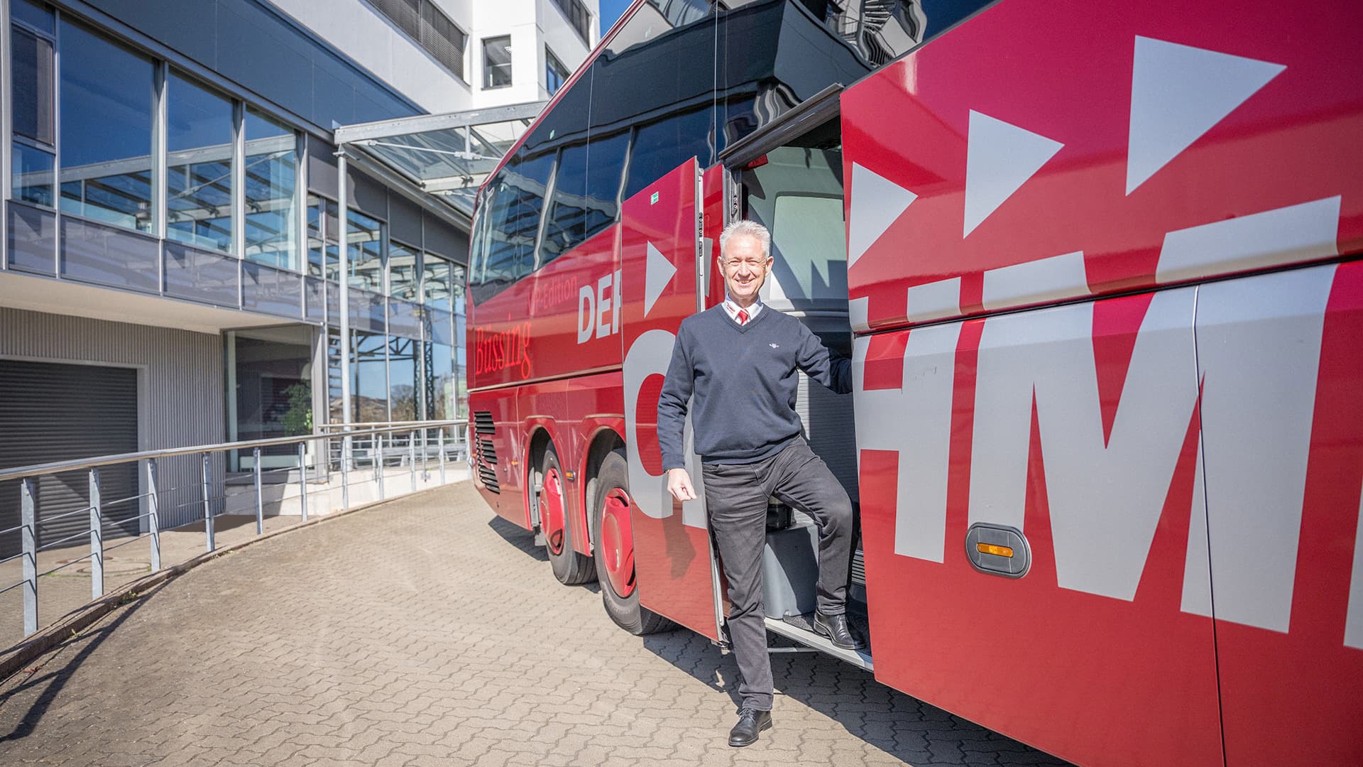 Busfahrer vor rotem DER SCHMIDT Bus