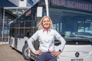 Busfahrerin mit cooler Pose vor weißem Linienbus bei DER SCHMIDT GRUPPE